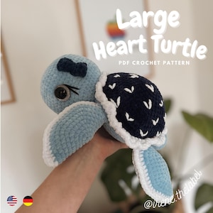 Könnte beinhalten: Eine hellblaue Häkelschildkröte mit einem marineblauen Panzer mit weißen Akzenten. Die Schildkröte hat eine kleine Schleife und Knopfaugen. Der Text "Large Heart Turtle PDF Crochet Pattern" wird angezeigt.