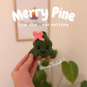 Può includere: Un albero di Natale verde all'uncinetto fatto a mano con un fiocco rosa, occhi neri e un viso sorridente. Il testo "Merry Pine" e "LOW SEW - PDF PATTERN" sono visualizzati in bianco. È visibile anche il nome Instagram @irene.thelabel.