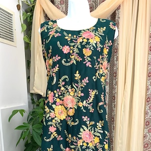 Könnte beinhalten: Ein ärmelloses grünes Kleid mit Blumenmuster und goldener Stickerei. Das Kleid hat eine passende grüne Palazzohose.