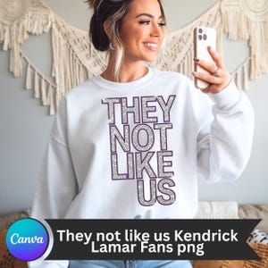 May include: White sweatshirt with the text "THEY NOT LIKE US" in silver glitter letters with purple outlines.