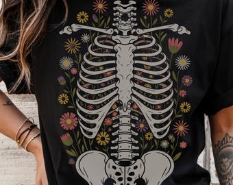 May include: Black t-shirt with a white skeleton design. The skeleton is surrounded by colorful flowers.