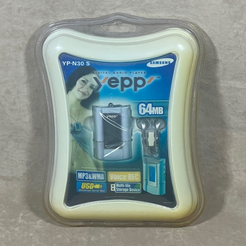 May include: A white and blue package for a Samsung YEPP YP-N30 S digital audio player. The player is silver and has a blue screen. The packaging also includes a pair of white earbuds and the text "64MB".