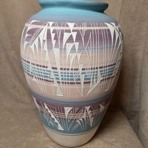 May include: A ceramic vase with a Southwestern design. The vase is decorated with white, blue, and purple geometric patterns.
