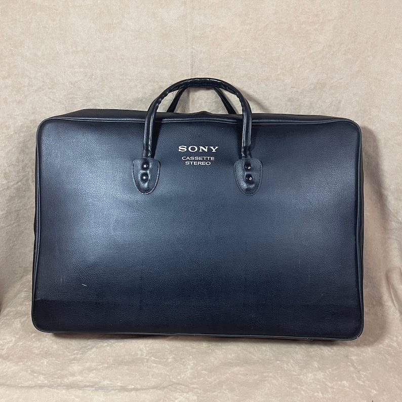 May include: Black leather carrying case with two handles and a silver label that reads "SONY CASSETTE STEREO".