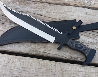 May include: A black and silver hunting knife with a serrated blade and a black leather sheath. The knife has a black wooden handle with a textured pattern.