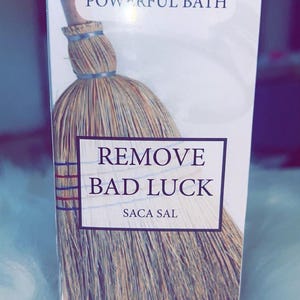 May include: A product box with the words "POWERFUL BATH" at the top and "REMOVE BAD LUCK SACA SAL" in a rectangular box below. The image features a broom with a wooden handle and straw bristles.