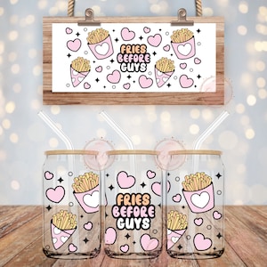 Może przedstawiać: Trzy przezroczyste szklanki z bambusowymi pokrywkami i słomkami. Każda szklanka ma różowy wzór serca z tekstem "Fries Before Guys" i kreskówkowym obrazkiem frytek w pojemniku.