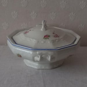 Puede incluir: Fuente de cerámica blanca con tapa, con diseño floral y ribete azul. La fuente tiene forma octogonal y un pequeño asa en la tapa. Una pieza clásica para servir.