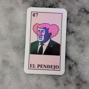 May include: A rectangular sticker featuring a caricature of a man with pink clown hair and a red nose. The number 47 is in the top left corner. The text "EL PENDEJO" is at the bottom.