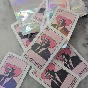 May include: A collection of pink and white cards featuring a caricature of a man with a clown nose and pink hair. The cards are labeled "47" and "EL PENDEJO". Some cards are scattered, and a holographic bag is in the background.
