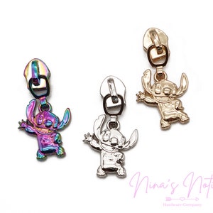 May include: Three zipper pulls featuring a cartoon character with large ears and a wide smile. The zipper pulls are in gold, silver, and iridescent colors.