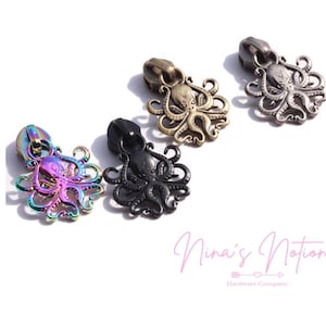 May include: Four zipper pulls in the shape of an octopus. The pulls are in different finishes: iridescent, black, antique brass, and gunmetal.