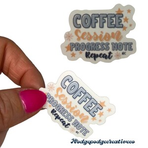 May include: A white sticker with a blue and orange design. The sticker says "Coffee Session Progress Note Repeat" with stars and flowers around the text.