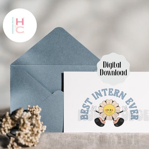 May include: A white card with blue text that reads "Best Intern Ever" with a cartoon flower with a smiley face and arms raised in the air. The card is on a light brown surface with a blue envelope and a white circle with the letters "HC" in pink and white.