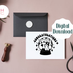 May include: A white card with black text that reads "Congratulations Future Stars" inside a black circle with stars. The circle is inside a black silhouette of a crystal ball. The card is on a pink surface with a black envelope and a wax seal.