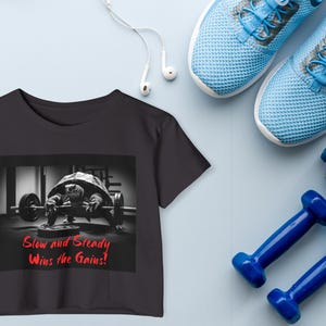 May include: Black cropped t-shirt with a graphic of a turtle lifting weights. The text "Slow and Steady Wins the Gains!" is printed in red on the shirt.