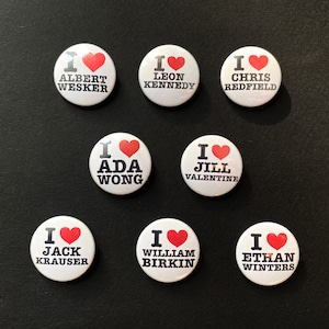 May include: Nine white round buttons with red hearts and black text. The text on the buttons reads: "I ♥ Albert Wesker", "I ♥ Leon Kennedy", "I ♥ Chris Redfield", "I ♥ Ada Wong", "I ♥ Jill Valentine", "I ♥ Jack Krauser", "I ♥ William Birkin", "I ♥ Ethan Winters".