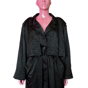 May include: A black trench coat with a notched collar, button closure, and a belt at the waist. The coat has long sleeves and a textured fabric. The coat is displayed on a mannequin.