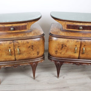 Könnte beinhalten: Zwei vintage Nachttische aus Holz mit geschwungenen Fronten, Glasplatten und einer Schublade. Die Tische haben ein Wurzelholzfurnier und Messingbeschläge.