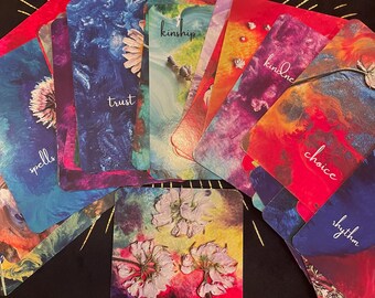 May include: A colorful deck of oracle cards with the words "Divine Line Oracle" and "Connecting You To Your Divine Powers" on the front. The cards feature a variety of floral designs and watercolor backgrounds.