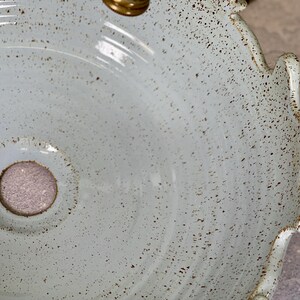 Puede incluir: Un lavabo de cer&aacute;mica azul claro con un esmalte moteado y un borde festoneado. El lavabo tiene un peque&ntilde;o agujero de drenaje en el centro.