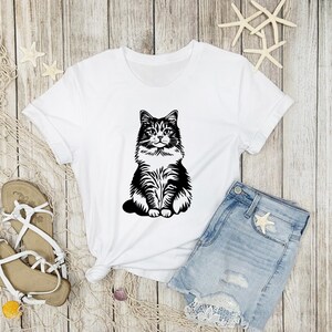 May include: White t-shirt featuring a black and white illustration of a cat sitting on a white background.