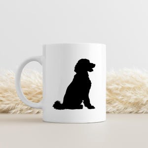 May include: White ceramic mug with a black silhouette of a poodle sitting. The poodle is facing to the right.