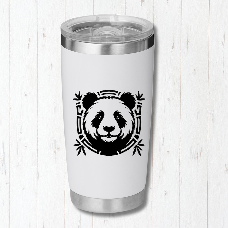 May include: A white travel tumbler with a silver lid and base. The tumbler features a black and white panda bear design in a square frame with bamboo leaves. The panda's face is centered on the tumbler.