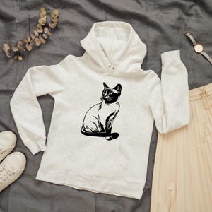 May include: A white hooded sweatshirt with a black silhouette of a cat sitting on the front.