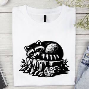 May include: A black and white illustration of a raccoon sleeping on a tree stump. The raccoon is curled up on the stump, with its tail wrapped around its body. The tree stump is surrounded by leaves and branches.