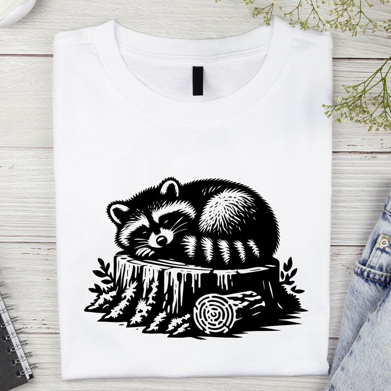 May include: A black and white illustration of a raccoon sleeping on a tree stump. The raccoon is curled up on the stump, with its tail wrapped around its body. The tree stump is surrounded by leaves and branches.