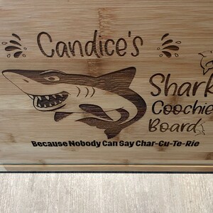 Puede incluir: Una tabla de cortar de bamb&uacute; personalizada con un dise&ntilde;o de tibur&oacute;n y el texto "Candice's Shark Coochie Board Because Nobody Can Say Char-Cu-Te-Rie".