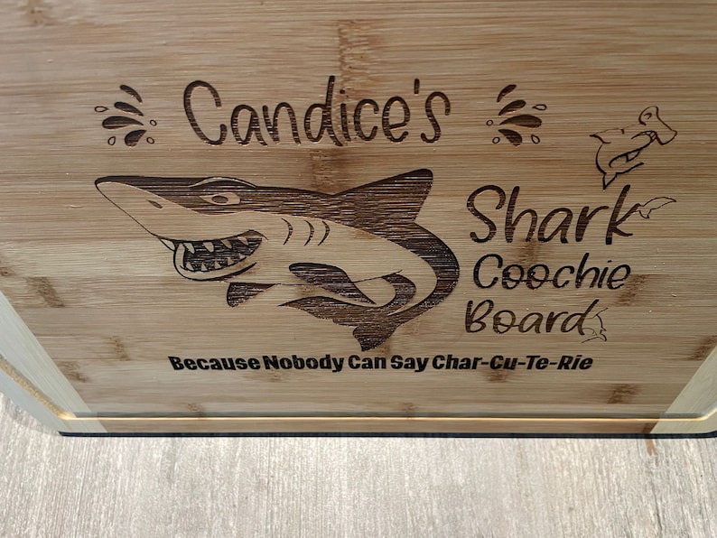 Puede incluir: Una tabla de cortar de bamb&uacute; personalizada con un dise&ntilde;o de tibur&oacute;n y el texto "Candice's Shark Coochie Board Because Nobody Can Say Char-Cu-Te-Rie".