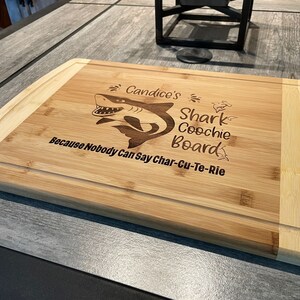 Puede incluir: Una tabla de cortar de bamb&uacute; personalizada con un gr&aacute;fico de tibur&oacute;n y el texto "Candice's Shark Coochie Board Because Nobody Can Say Char-Cu-Te-Rie".