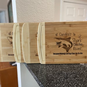 Puede incluir: Tres tablas de cortar de bamb&uacute; personalizadas con un dise&ntilde;o de tibur&oacute;n y el texto "Candice's Shark Coochie Board Because Nobody Can Say Char-Cu-Te-Rie".