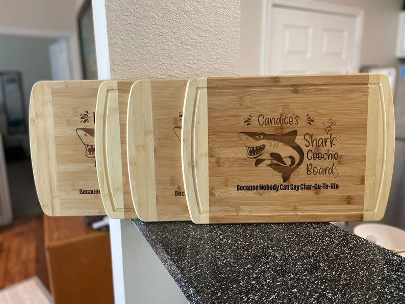 Puede incluir: Tres tablas de cortar de bamb&uacute; personalizadas con un dise&ntilde;o de tibur&oacute;n y el texto "Candice's Shark Coochie Board Because Nobody Can Say Char-Cu-Te-Rie".