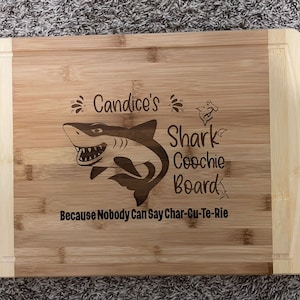 Puede incluir: Una tabla de cortar de bamb&uacute; personalizada con un gr&aacute;fico de tibur&oacute;n y el texto "Candice's Shark Coochie Board Because Nobody Can Say Char-Cu-Te-Rie".