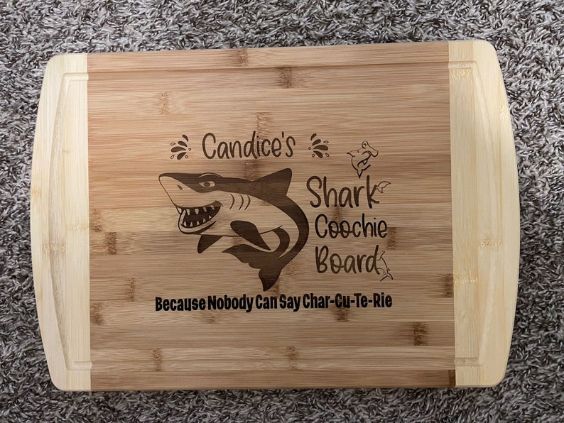 Puede incluir: Una tabla de cortar de bamb&uacute; personalizada con un gr&aacute;fico de tibur&oacute;n y el texto "Candice's Shark Coochie Board Because Nobody Can Say Char-Cu-Te-Rie".