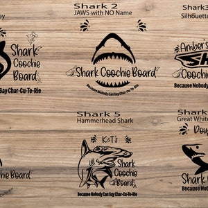 Puede incluir: Seis dise&ntilde;os de tiburones diferentes sobre un fondo de madera. Cada dise&ntilde;o presenta una silueta de tibur&oacute;n con el texto "Shark Coochie Board" y un nombre o frase personalizado. El texto dice "Because Nobody Can Say Char-Cu-Te-Rie".