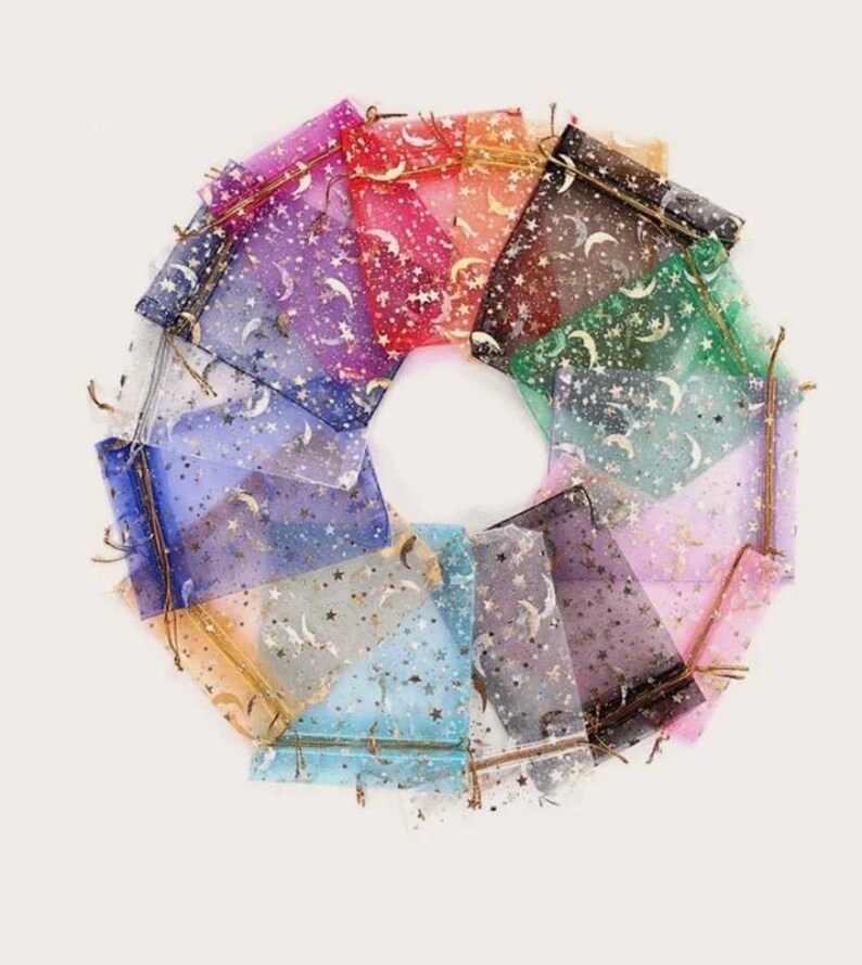 Peut inclure: Un ensemble de 12 petits sacs en organza transparent avec des paillettes dor&eacute;es et un motif de croissant de lune et d'&eacute;toiles. Les sacs sont de diff&eacute;rentes couleurs, notamment rose, bleu, violet et vert.