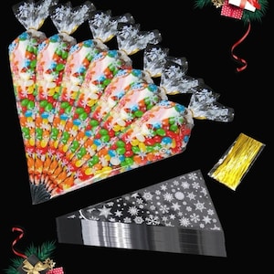 May include: A set of clear plastic cone-shaped bags with a snowflake design. The bags are filled with colourful candy and are tied with gold ribbon. The set also includes a roll of gold ribbon and a flat sheet of snowflake-patterned bags.