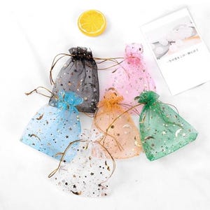 Peut inclure: Six petits sacs cadeaux en tulle en forme d'&eacute;toile avec des accents de paillettes dor&eacute;es. Les sacs sont de diff&eacute;rentes couleurs&nbsp;: noir, rose, bleu clair, blanc, vert et orange.