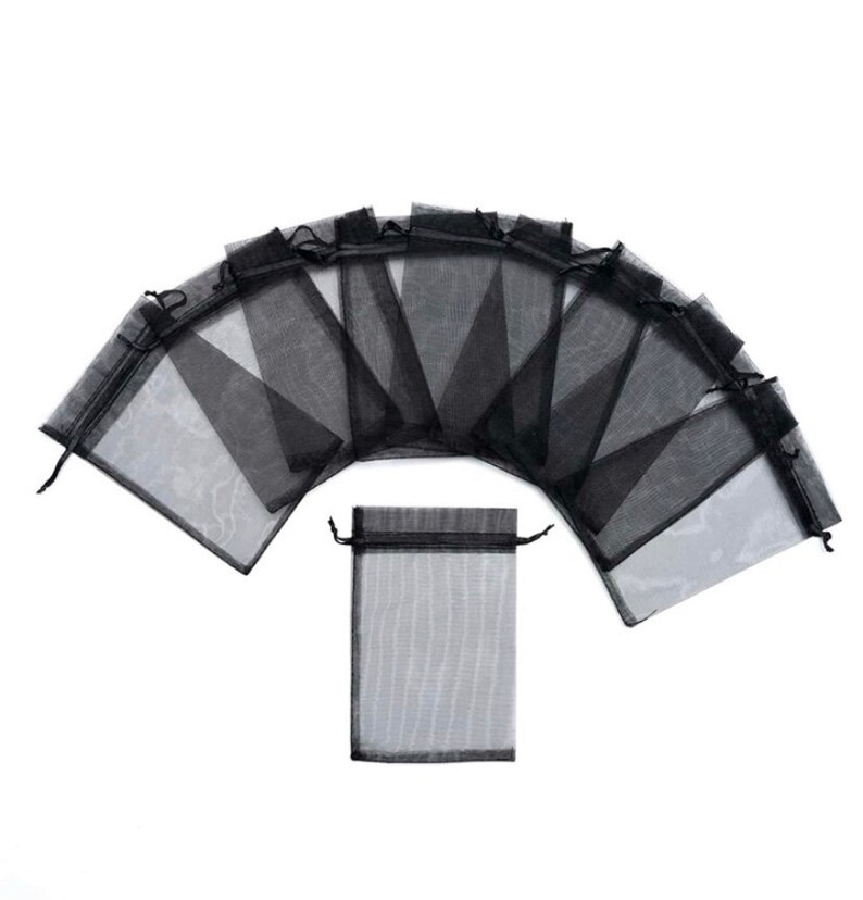 Peut inclure: Dix sacs cadeaux en organza noir transparent avec cordon de serrage. Les sacs sont dispos&eacute;s en demi-cercle avec un sac au centre.