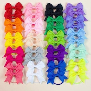 Könnte beinhalten: Ein Set mit 24 bunten Haarbändern mit Gummibändern. Die Schleifen sind aus Band und in verschiedenen Farben erhältlich, darunter Rot, Orange, Gelb, Grün, Blau, Lila, Rosa und Weiß.
