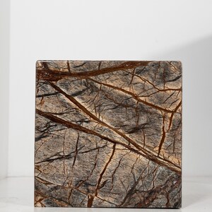 May include: A square, brown and gray marble tile with a natural veined pattern.
