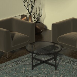 May include: Two brown velvet armchairs with metal legs face each other across a glass-top coffee table with a black metal frame. A small wooden side table with a patterned surface sits next to one of the chairs. A blue and green patterned rug covers the floor.