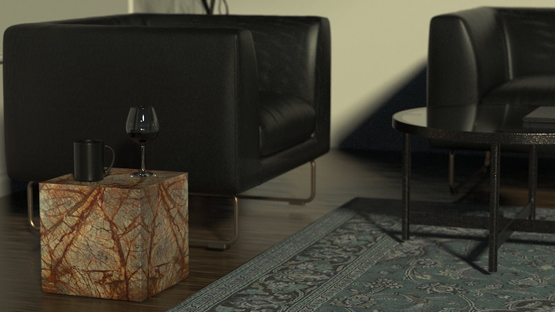 May include: A small, square, brown and orange marble side table with a black mug and a wine glass on top. The table is in front of a black leather armchair and a black leather sofa.
