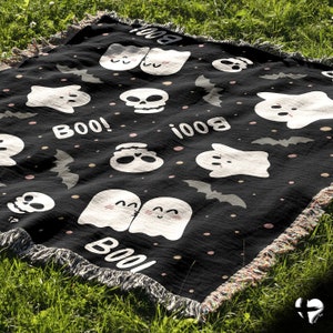May include: Black and white Halloween themed throw blanket with a repeating pattern of ghosts, skulls, bats, and the word "BOO!"