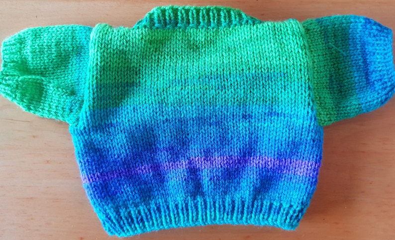 May include: A hand-knitted sweater in a gradient of green, blue, and purple.