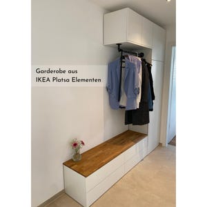 Beispiel für ein Projekt mit einer Massivholzdeckplatte nach Maß aus Eiche von Omformo. Hier als Garderobenlösung mit einem IKEA Platsa mit integrierter Sitzbank. Dekoriert mit Pflanzen und Jacken um ein Wohnbeispiel für einen modernen Eingangsbereich darzustellen.